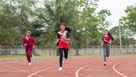 Group of teenagers wear sport cloth run on racetrack, jumping and exercise for health. Healthcare and sport concept. Free space for your text.