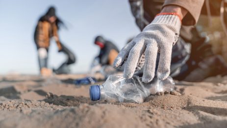 Volunteer man collecting trash on the beach. Ecology concept