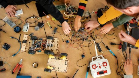 Top view of a table with engineering tools and details lying on it. Children working with wires, constructing diy robot in class. Smart kids and STEM education. Science and people concept